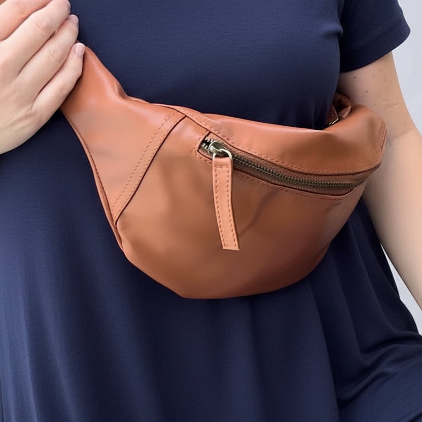 Brown leather fanny pack worn by a person in a navy blue shirt.
