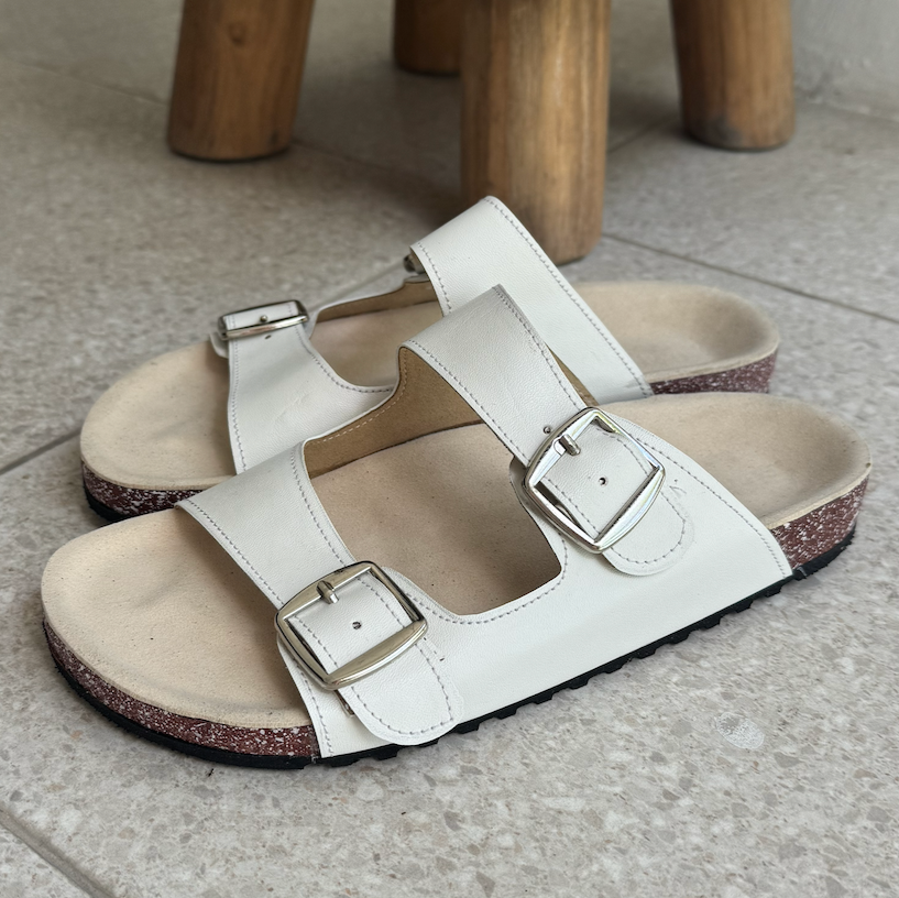 White sandals with buckles on a tiled floor