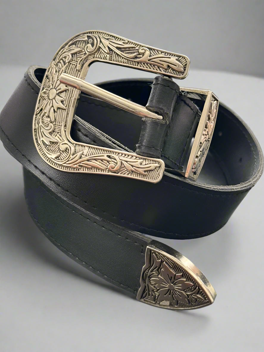 A vegan leather western belt with a black strap and a silver-colored ornate buckle, on a dark background.