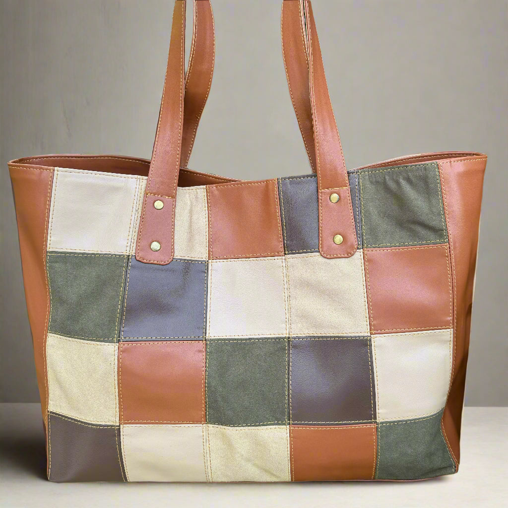 A vegan leather tote bag with a patchwork design featuring tan and green colors, and brown straps.