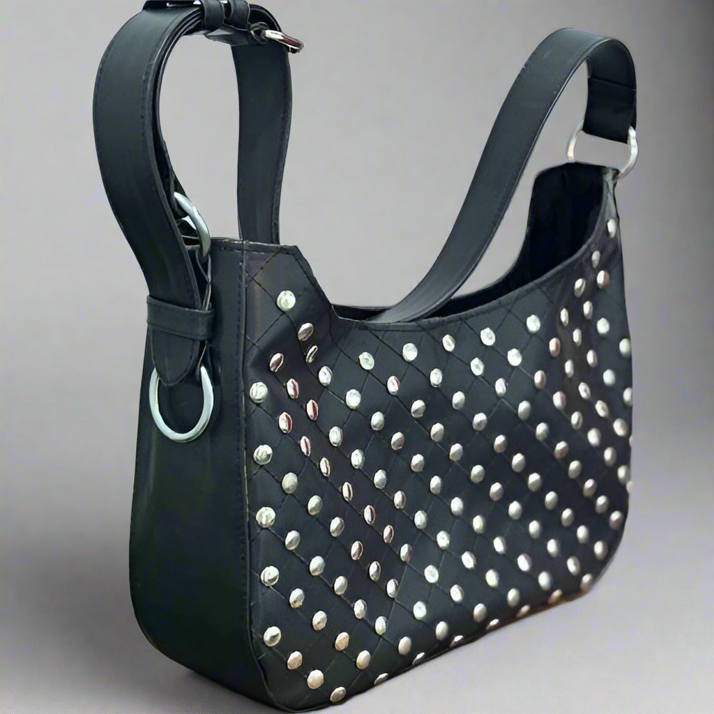 A black vegan leather shoulder bag with a studded design and an adjustable strap