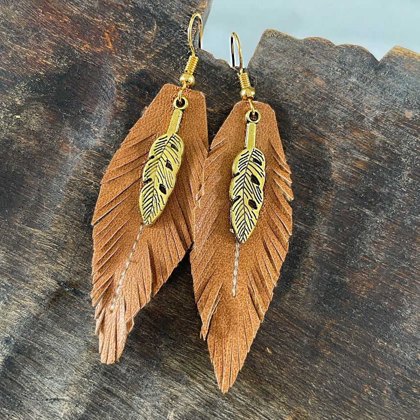 Gold coloured sterling silver earring hooks and brown vegan eco leather cut in the shape of a feather. Embrace cruelty-free fashion with these stunning handmade earrings that add a touch of boho to any outfit. Gold coloured sterling silver hooks and vegan leather. Bohostyle Vegan Handmade Accessories and Jewellery.